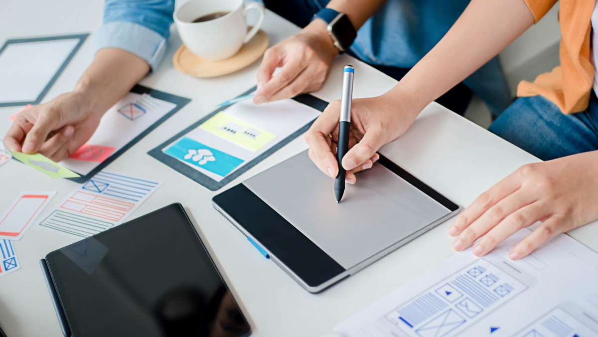 Imagen de un equipo de Diseñadores Trabajando en un Estudio Creativo, Rodeado de Tecnología y Herramientas de Diseño