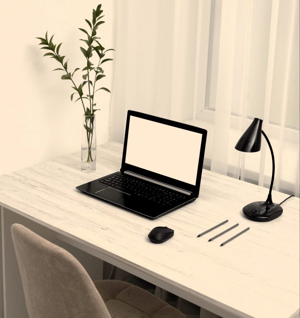 escritorio impecable con una computadora portátil, una planta pequeña y una taza de café