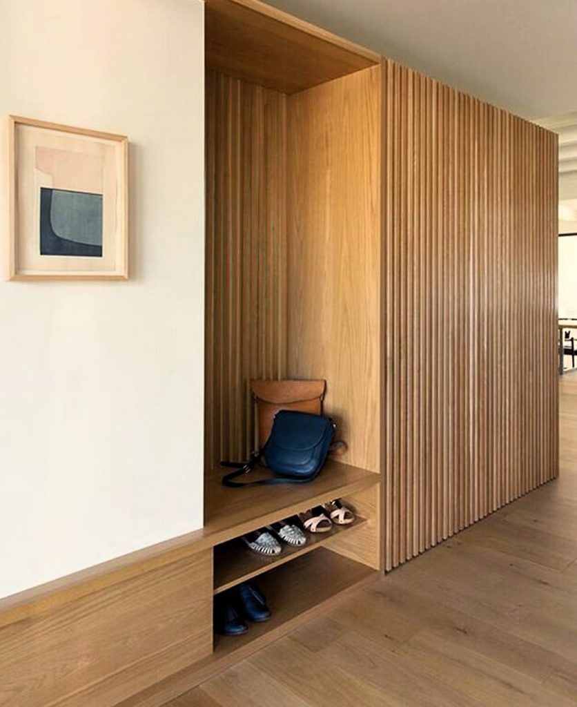 Pasillo decorado con alistonado de madera que oculta puertas deslizantes hacia un armario de gran capacidad