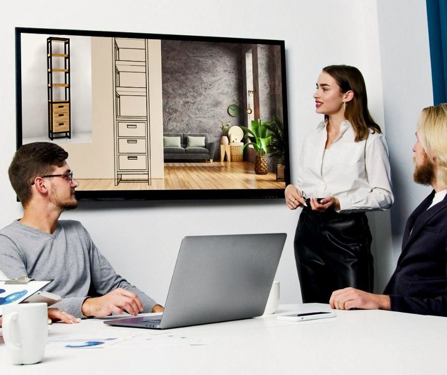Profesionales de estudio de diseño industrial y e interiorismo interactuando con un cliente, mostrando el diseño en el monitor