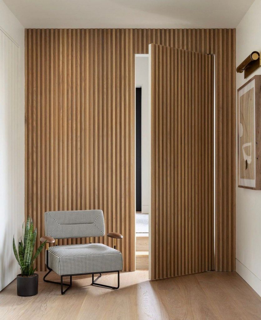 Pequeño rincón de lectura con pared de alistonado de madera que oculta una puerta secreta
